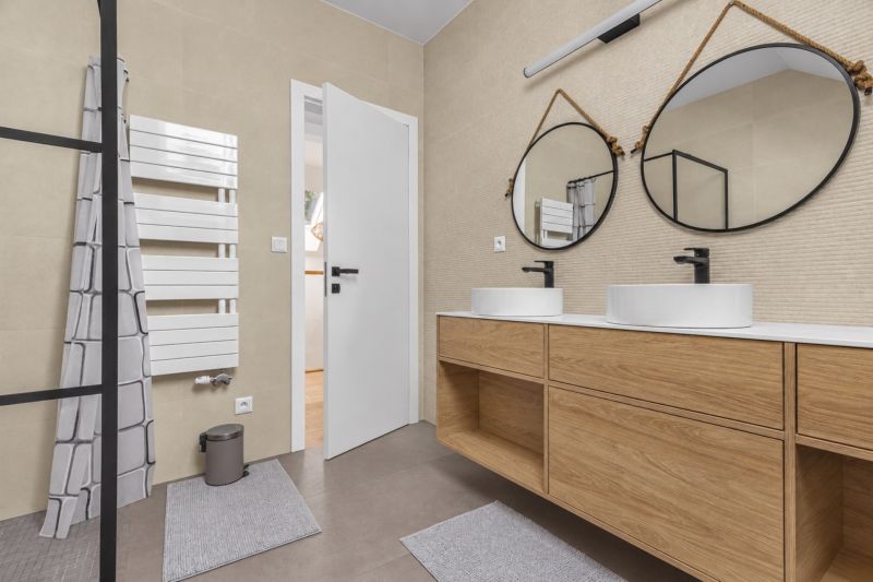 A bathroom with round mirrors and a wooden decor floor in a family house.