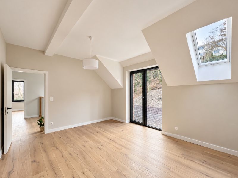 A bright room in a family house with a French window and a floor with a wooden decor.