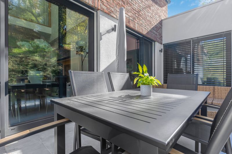 A terrace of a family house with modern furniture and greenery in a flower pot.