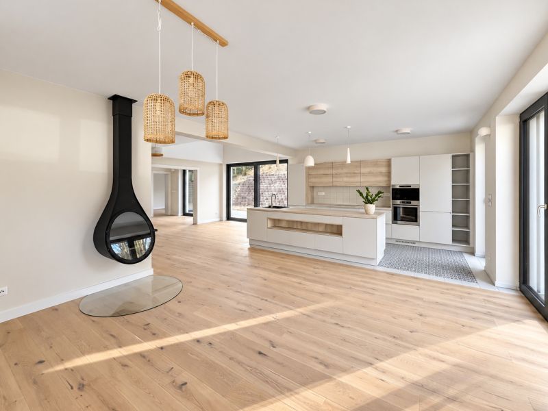 Interior of a family house with a fireplace, kitchen, and wooden decor flooring.