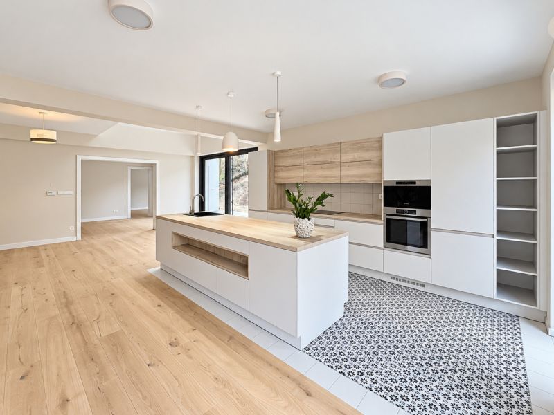 A kitchen in a family house with an island, white cabinets, and a wood-patterned floor.