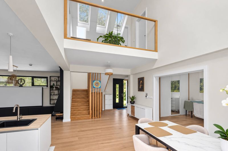 Bright living room with wood-patterned flooring and a staircase in a family house.