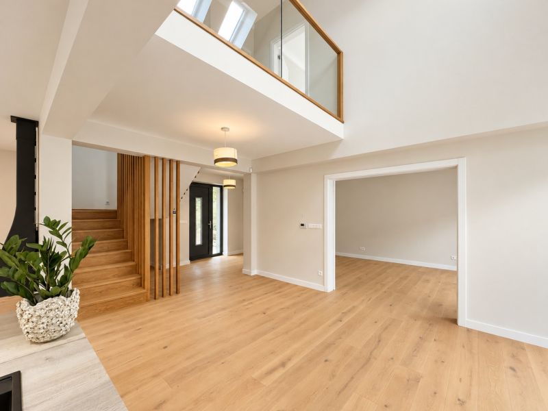 Interior of a family house with an open ceiling, stairs, and floor with wooden decor.