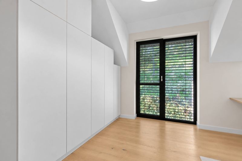 Interior of a family house with built-in wardrobes, a large window, and a floor with a wooden decor.