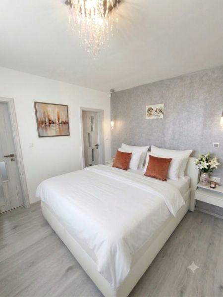 A bedroom in a family house with a wooden decor floor and an elegant bed.