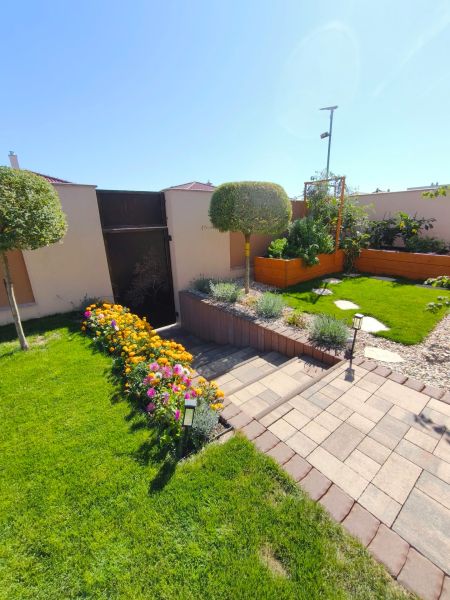 The garden of a family house in Martin nad Žitavou with flower beds and a paved walkway.
