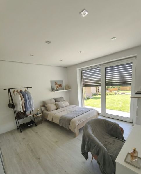 A bright bedroom in a family house with wood-decor flooring and large windows.
