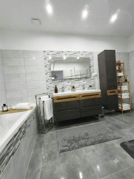 A bathroom in a family house with a large mirror, a bathtub, and decorative tiles.
