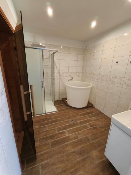 A bathroom with a bathtub and a shower, a floor with a wooden decor in a family house.