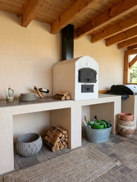 The exterior of a family house in Martin nad Žitavou with an outdoor oven and firewood.
