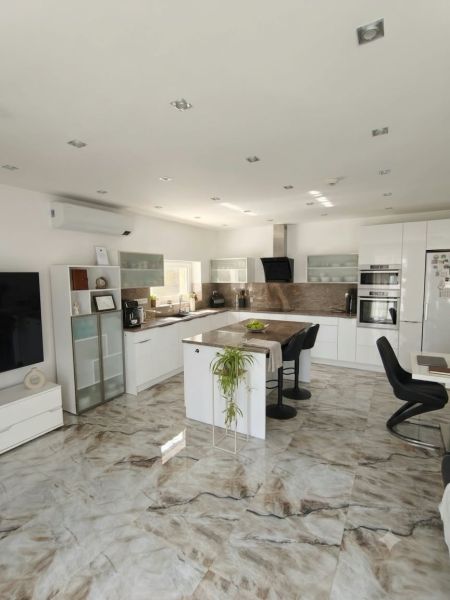 A family house kitchen with a marble floor, a large island, and built-in appliances.