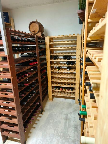 A wine cellar in a family house with wooden racks and a wine barrel.