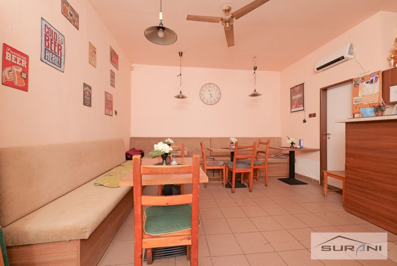 A café with wooden chairs, decorative posters, and a clock on the wall.