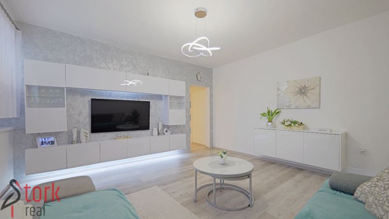 Living room with white gloss furniture and a wood-decor floor.