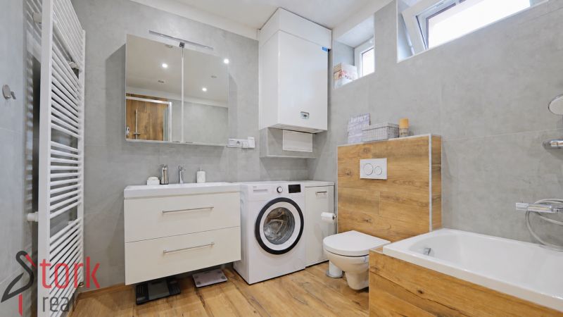 A bathroom in a 4-room apartment with a wooden decor floor and a washing machine.