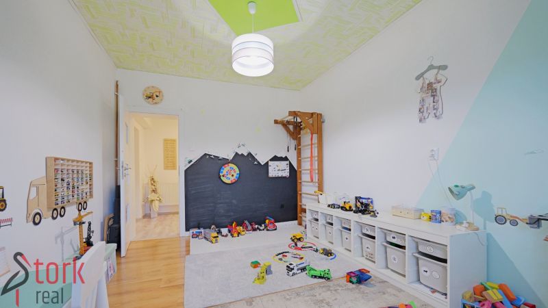 Children's room in a 4-room apartment with a wooden decor floor, toys, and storage boxes.