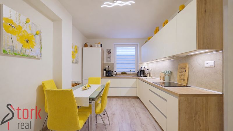 Kitchen in a 4-room apartment, wooden decor flooring, yellow accessories, flower paintings.