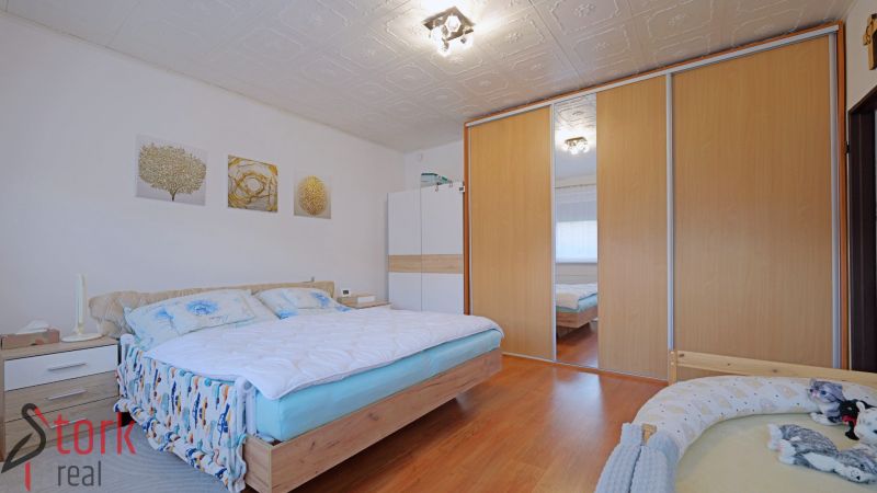 Bedroom with a built-in wardrobe, bed, and floor with wood decor in a 4-room apartment.
