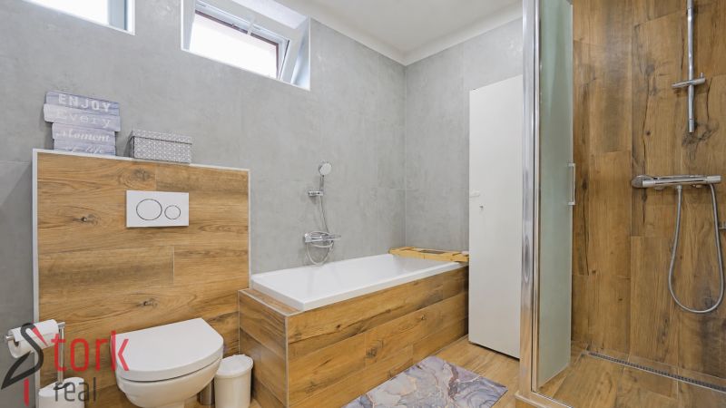 A bathroom with a shower and a bathtub with a wooden decor floor in a 4-room apartment.
