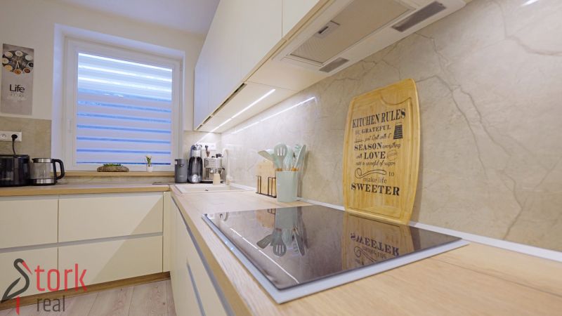 A bright kitchen with an induction cooktop, wall decoration, and appliances in a 4-room apartment.