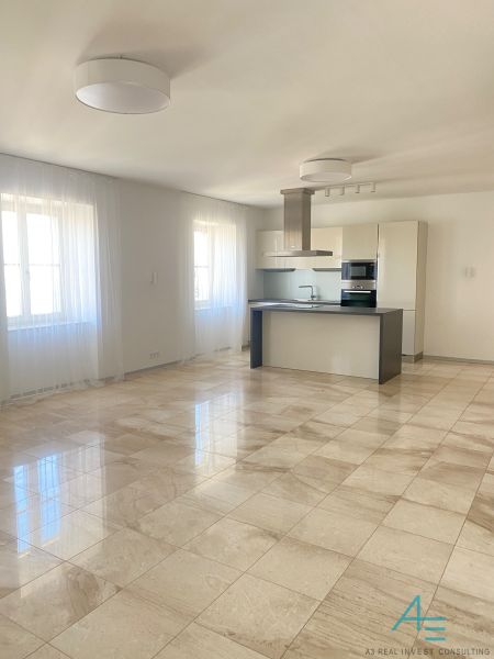 The image shows a spacious kitchen and living room in a three-room apartment on Hlboká Street.