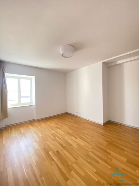 An empty room with a wooden floor and a window on Hlboká Street, a 3-room apartment.