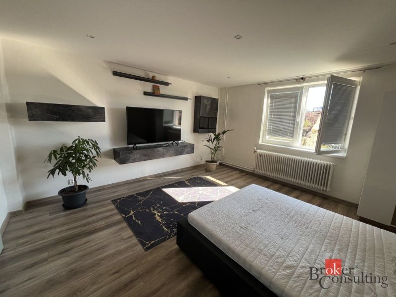 A room in a 4-room apartment with a wooden decor floor and a television.