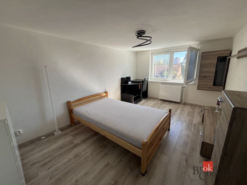 A room in a 4-room apartment with a bed, a table, and a floor with a wooden decor.