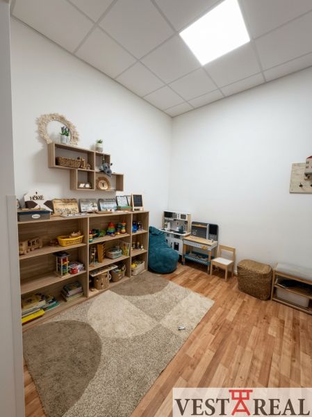 Children's corner in the office with shelves full of toys, floor with wooden decor.