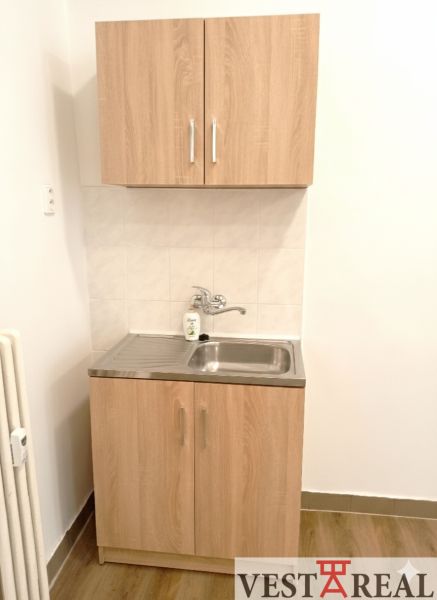 Small kitchen unit with a sink and cabinets, floor with wood decor.