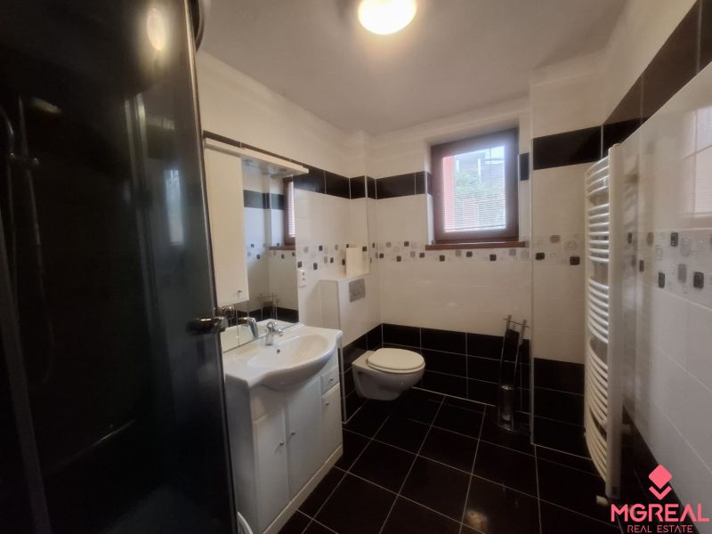 Bathroom with a window, shower, sink, and toilet in a family house.