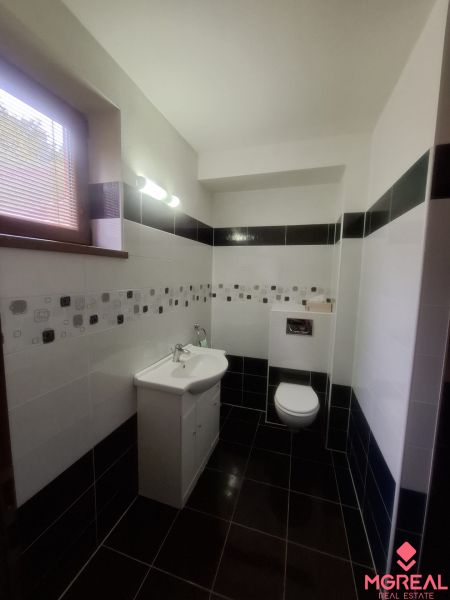 A bathroom in a family house with a sink, toilet, and black and white tiles.