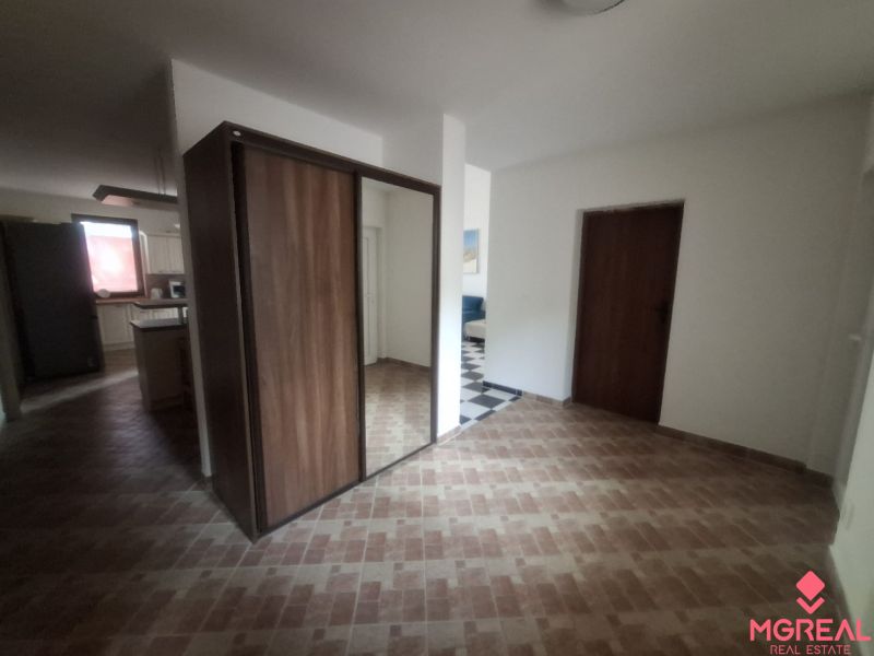 The hallway of a family house with a wooden decor floor and a mirrored wardrobe.