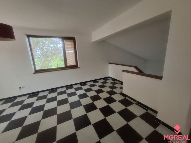 A room in a family house with a window and a staircase, checkered tiles.