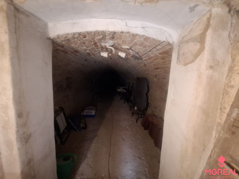 A brick cellar in a family house with stored items on the floor.