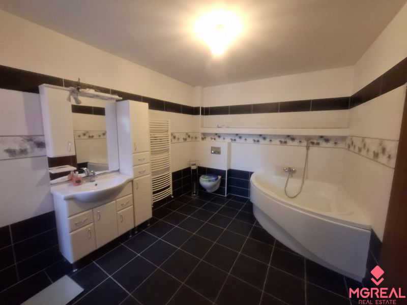 Bathroom with a bathtub, sink, and storage space in a family house.