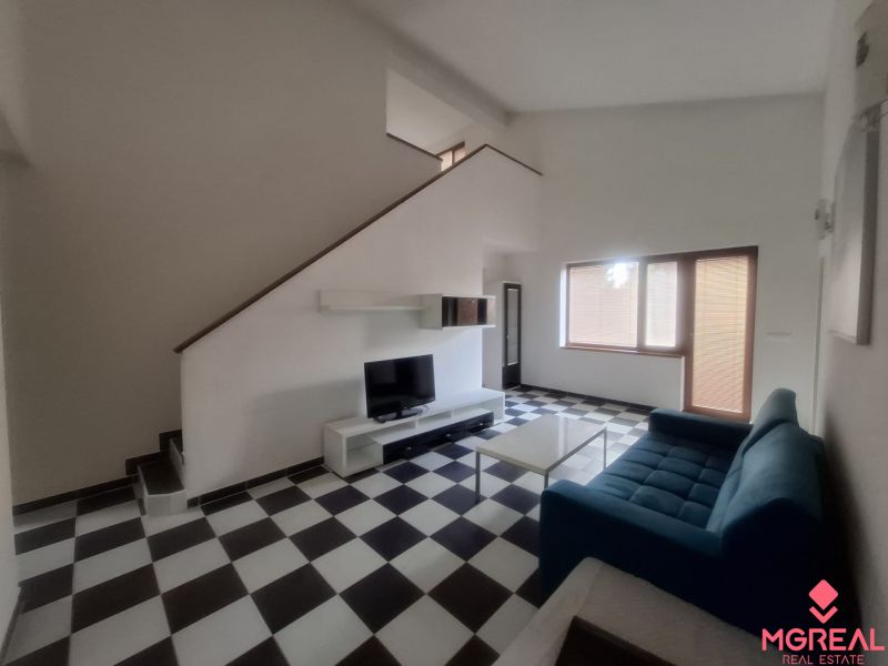 A living room in a family house with a blue sofa and black and white checkered floor.