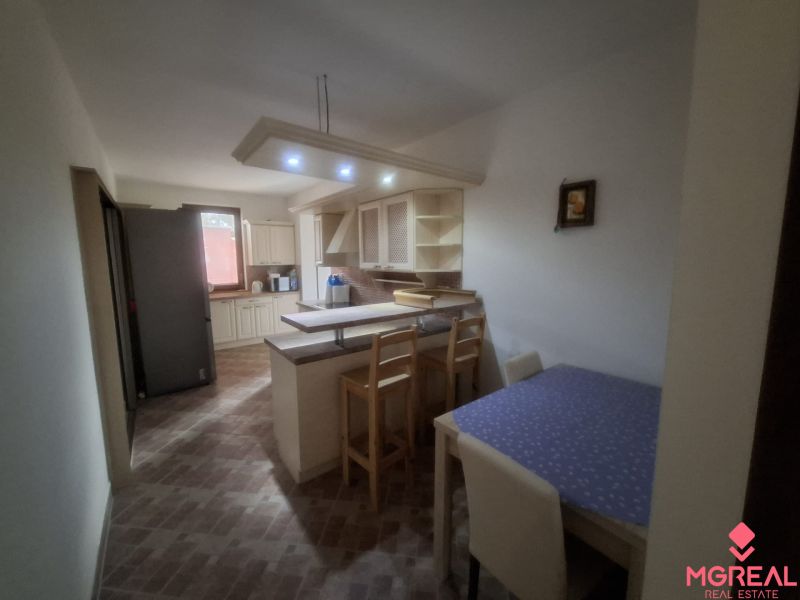 A kitchen in a family house with a bar counter, lighting, and a dining table.