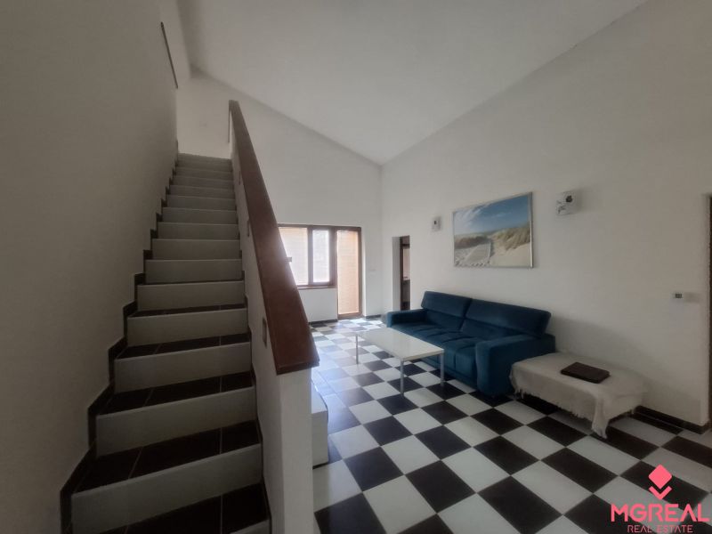 Staircase and living room with black and white flooring in a family house.