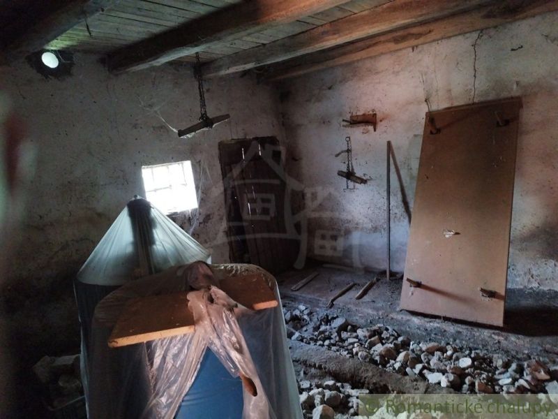 The interior of a cabin with a holey floor, wooden ceiling, and stored materials.