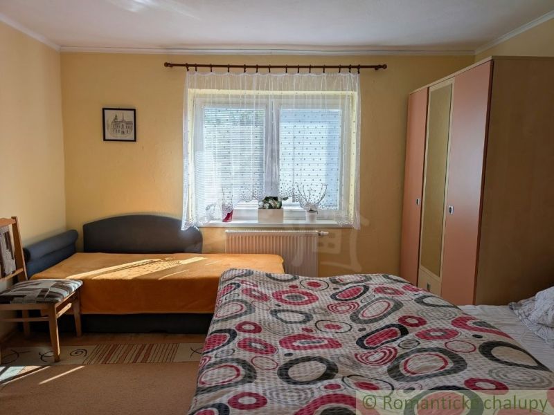 Bedroom in a family house with a bed, armchair, wardrobe, and window sill with decorations.