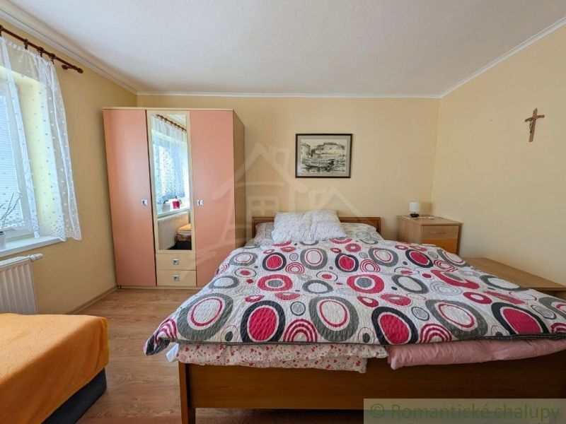 Bedroom in a family house with a bed, a couch, a wardrobe, and wall decorations.
