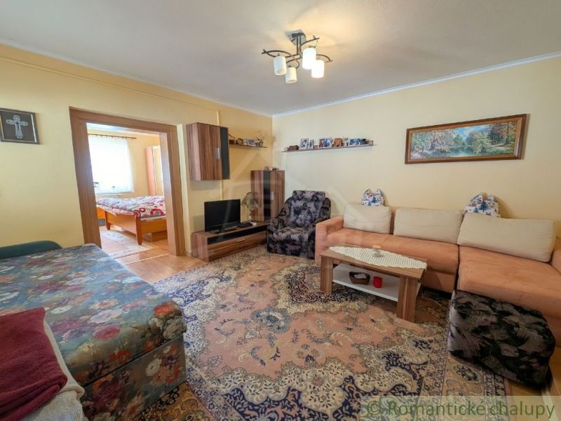Living room of a family house with a comfortable sofa and a view into the bedroom.