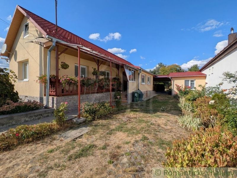 A family house in Cabov with a renovated porch and a flower bed in the garden.