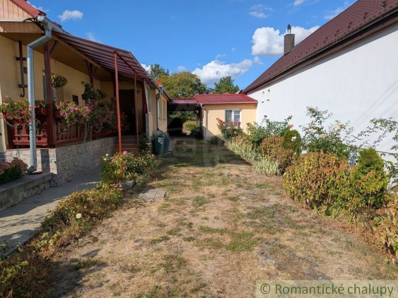 A family house in Cabov with a veranda and a garden full of flowers and greenery.