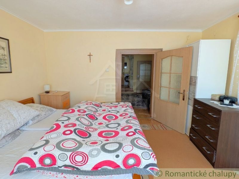 Bedroom with a bed, dresser, and wooden decor in a family house.