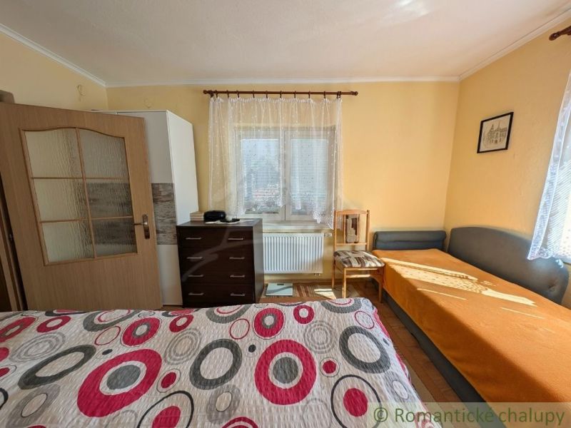 A room in a family house with simple furniture and a colorful bedspread.