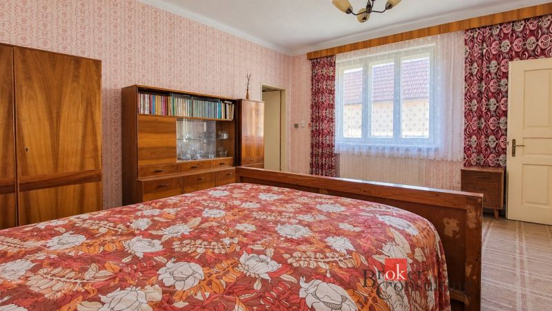 A bedroom in a family house with wooden furniture and a floral bedspread.