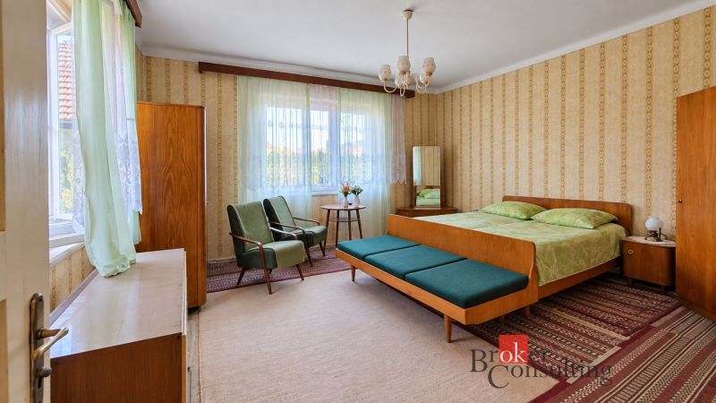A bedroom with retro furniture and floral patterns in a family house.