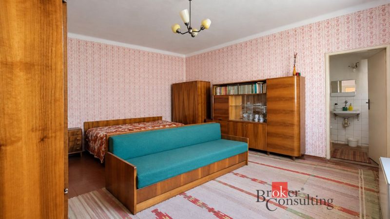 A room in a family house with retro furniture, patterned wallpaper, and a sofa.